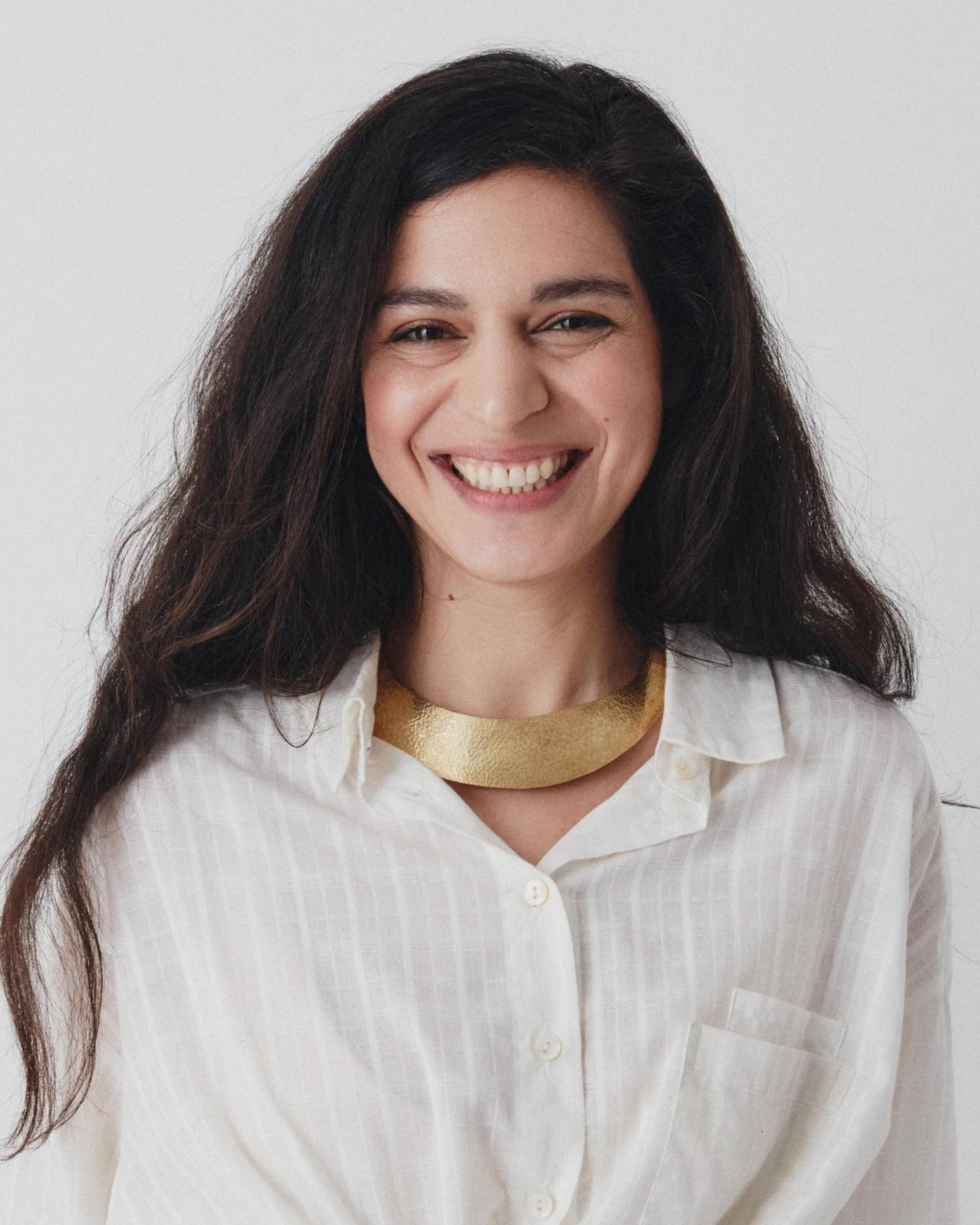 Woman wearing a white shirt and blue pants against a plain background