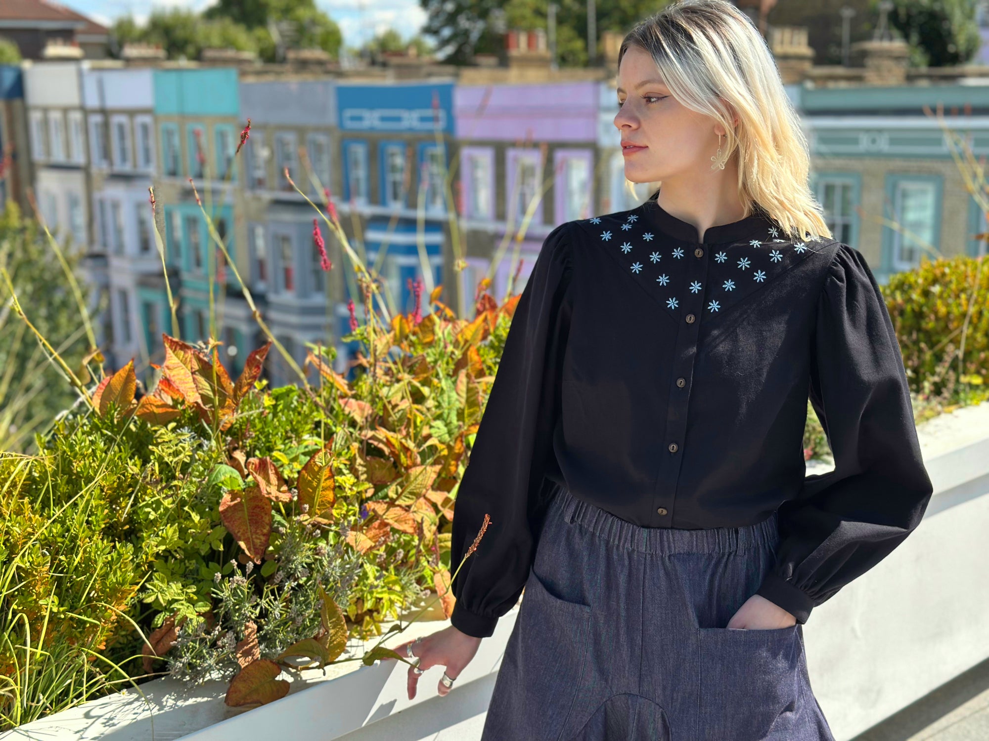 Woman wearing a black blouse with floral embroidery in an outdoor setting