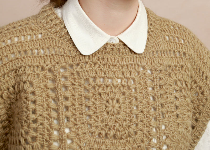 Close-up shot showing the geometric crochet square motif and collar detail on the natural corn yellow vest