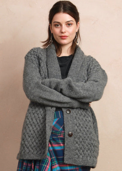 Model wearing the natural charcoal grey basket stitch hand-knit cardigan styled over a pattern skirt