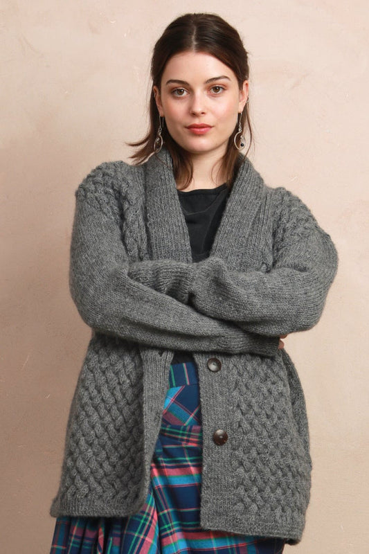 Model wearing the natural charcoal grey basket stitch hand-knit cardigan styled over a pattern skirt