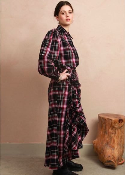 Side view of the berry and black check Rebel Skirt styled hitched up into a ruffled, asymmetrical drape, paired with a matching long-sleeve blouse and black boots