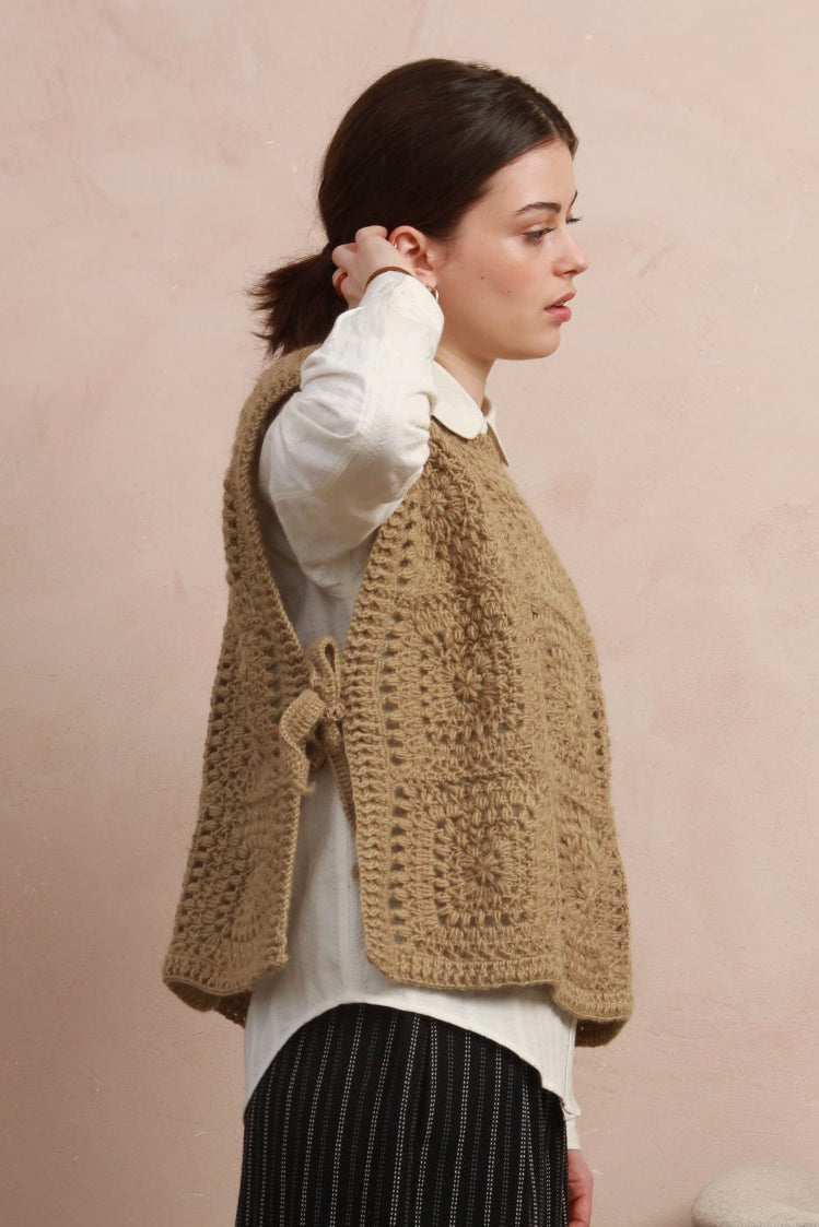 Side profile view of model wearing the boxy natural corn yellow crochet square vest showing tie detail