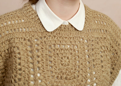 Close-up shot showing the geometric crochet square motif and collar detail on the natural corn yellow vest