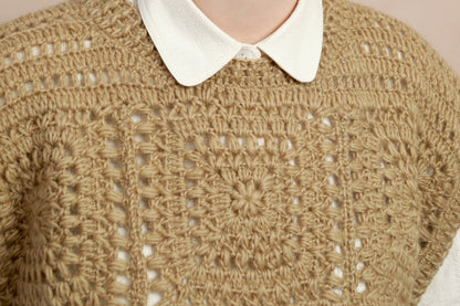 Close-up shot showing the geometric crochet square motif and collar detail on the natural corn yellow vest