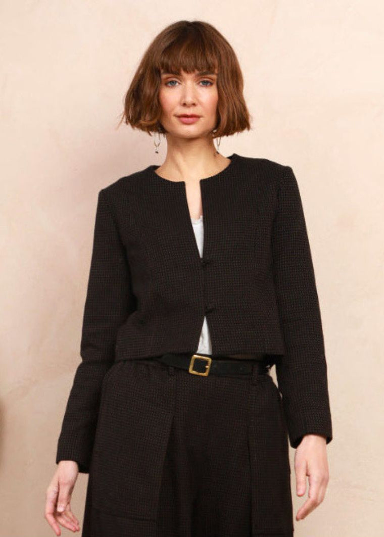 Model wearing the cropped collarless jacket in black and brown handwoven jacquard weave