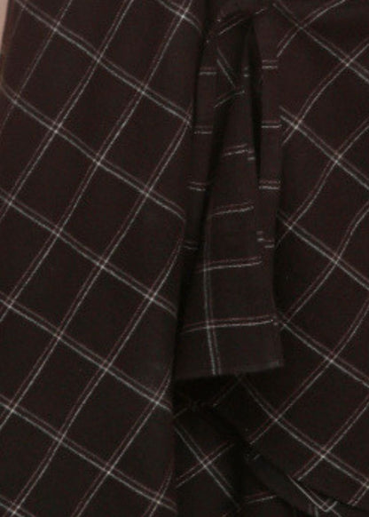 Close-up of a black plaid fabric with thin white and gray intersecting lines, showing folds and texture.