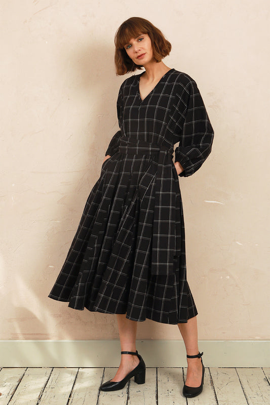 Model wearing the black and white check Penny Dress with V-neckline and long volume sleeves