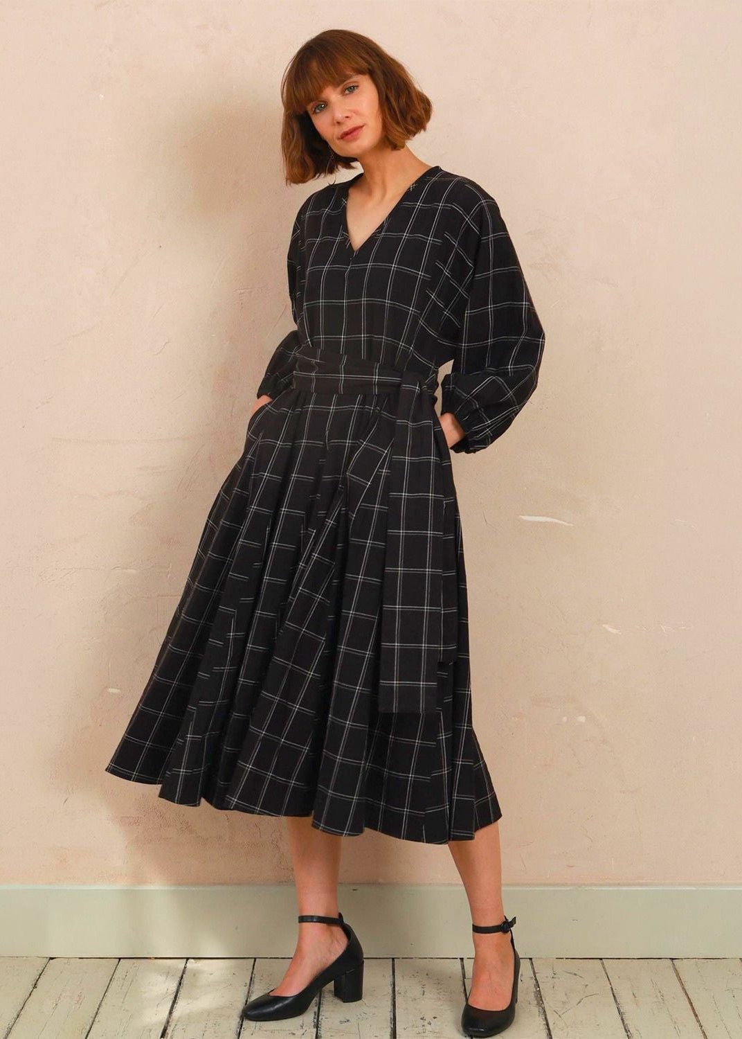 Model wearing the black and white check Penny Dress with V-neckline and long volume sleeves