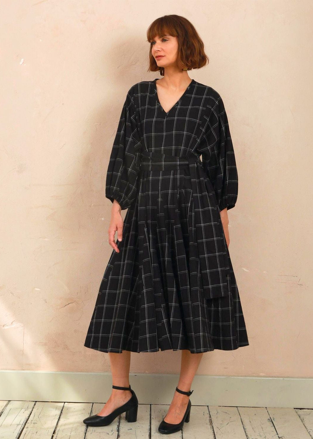 Model wearing the black and white check Penny Dress styled with black heels