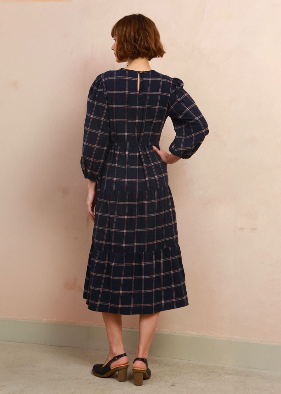 Back view of model wearing the navy and pink check Roseby midi dress showing high neckline and skirt drape