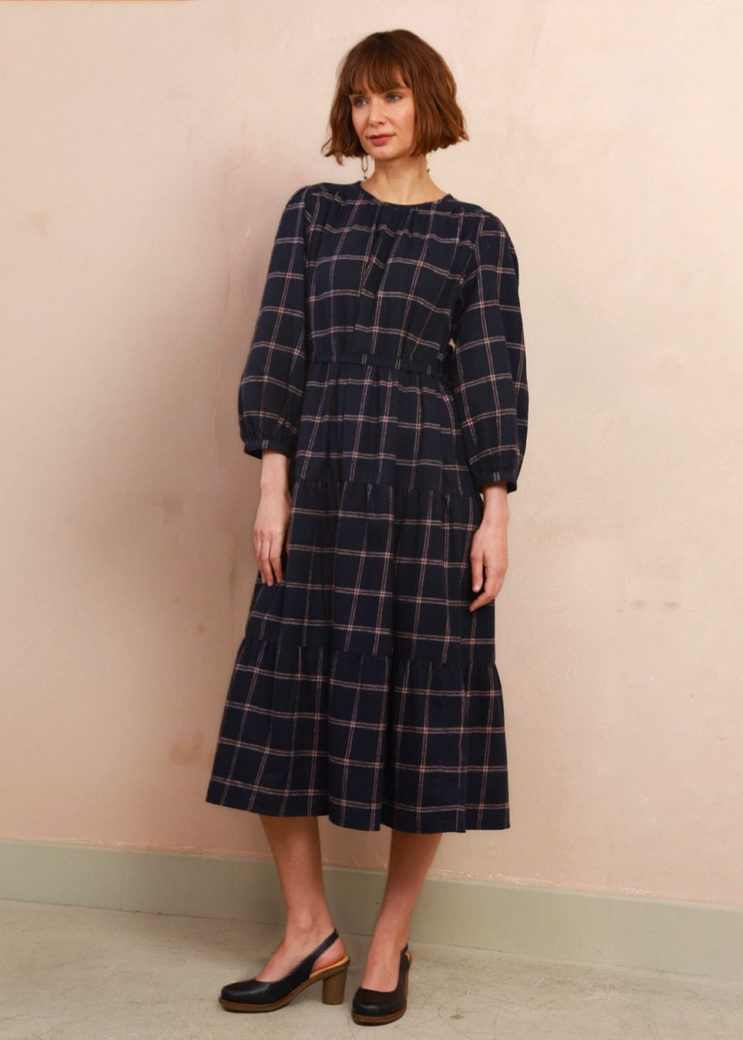Model wearing the handwoven navy and pink check Roseby midi dress with three-quarter volume sleeves
