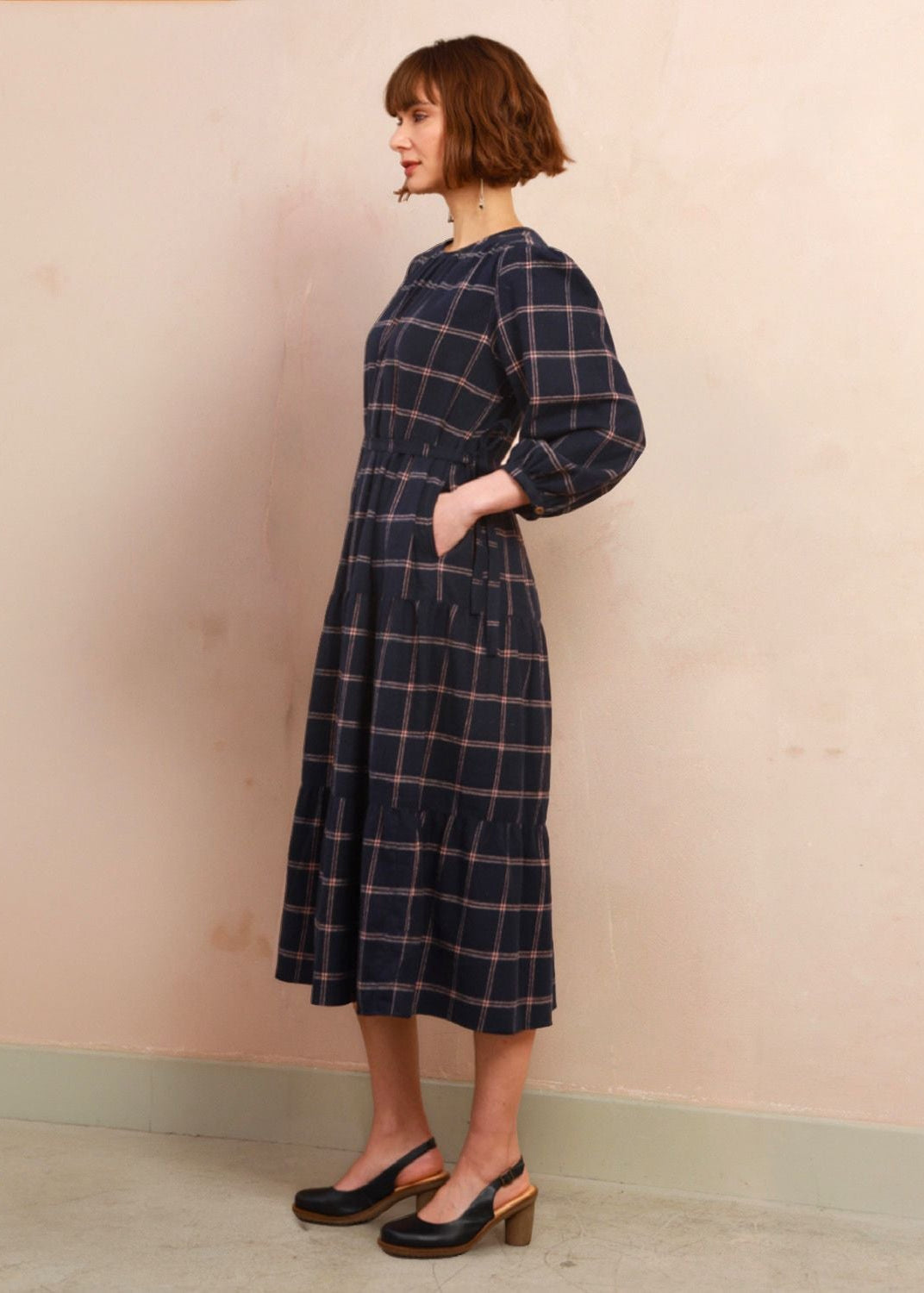 Side profile view of model wearing the navy and pink check Roseby Dress showing defined waist and tiered skirt