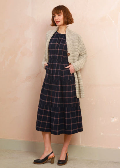 Model wearing the navy and pink check Roseby Dress styled with an cream knit cardigan layered over top