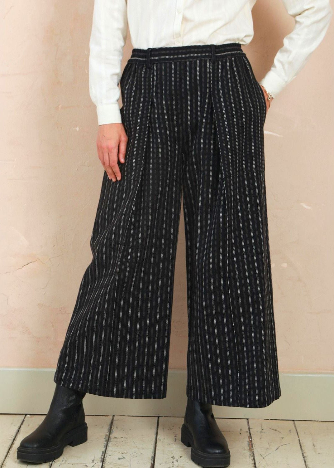 Front view of model wearing the black stripe Sarah Trousers with wide-leg silhouette and front pleats