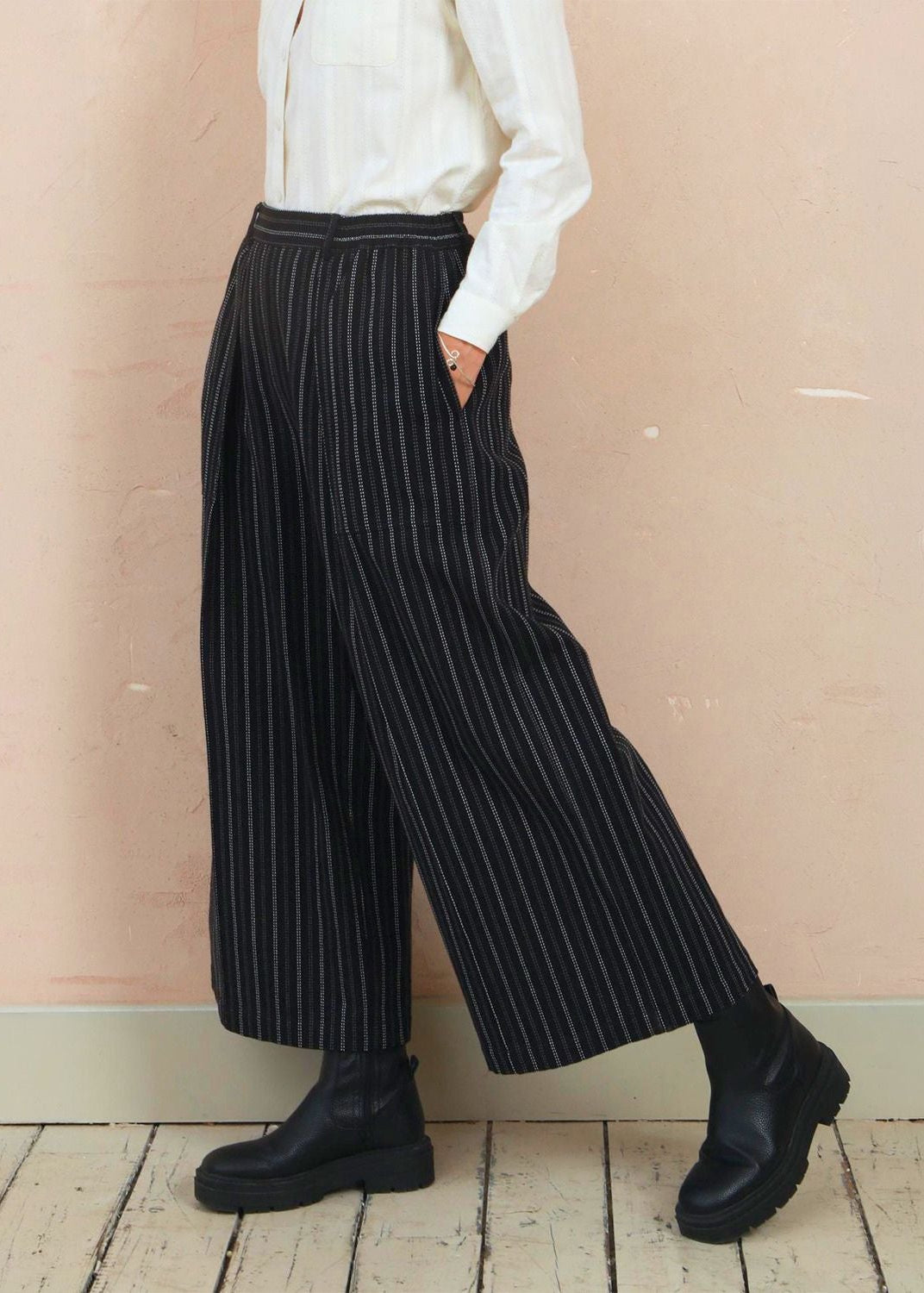 Side profile of model wearing the black stripe Sarah Trousers with dark footwear
