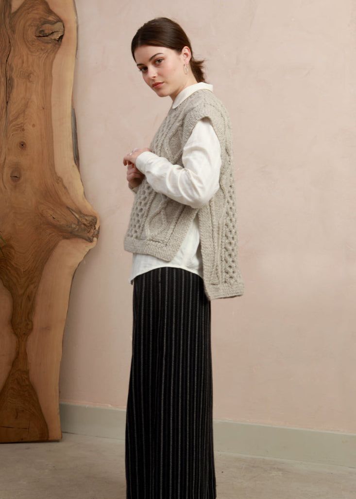 Side view of model wearing the natural light grey hand-knit slipover styled with wide-leg black trousers