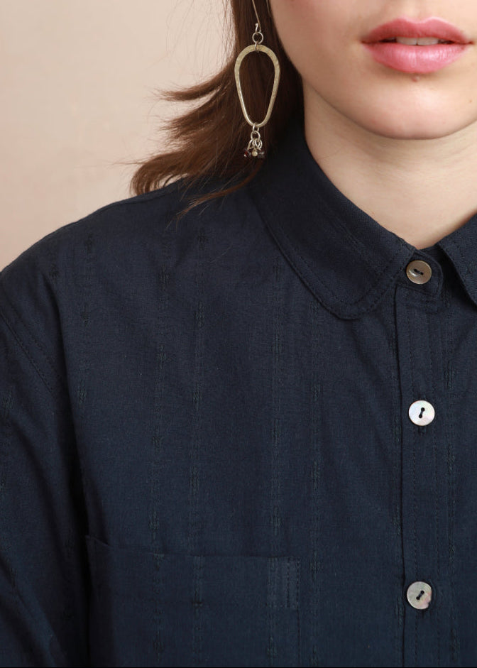 Close-up shot of model focusing on the rounded collar and deep navy fabric of the Sylvia Shirt