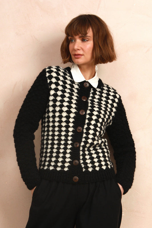 Model wearing the two-tone black and white hand-knit cardigan over a white collared shirt