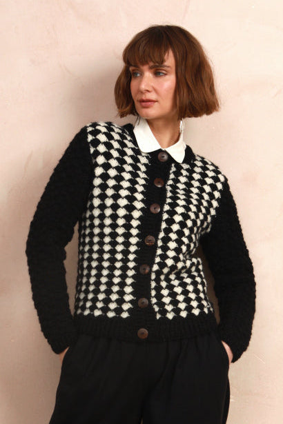 Model wearing the two-tone black and white hand-knit cardigan over a white collared shirt
