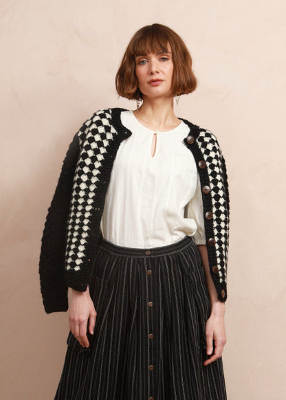 Front view of model wearing the black and white textured knit cardigan over the shoulders