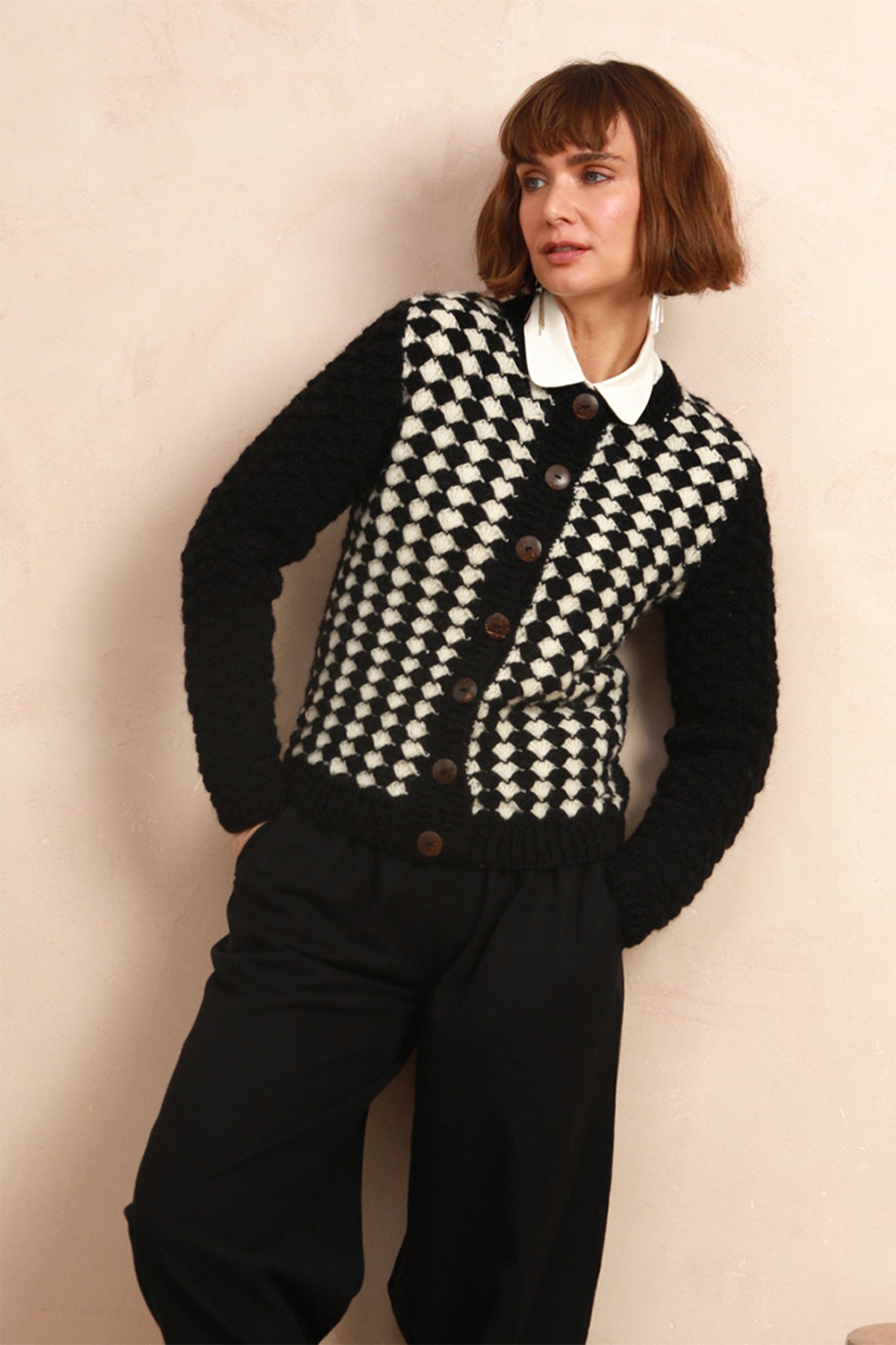 view of model wearing the black and white hand-knit cardigan styled with black trousers