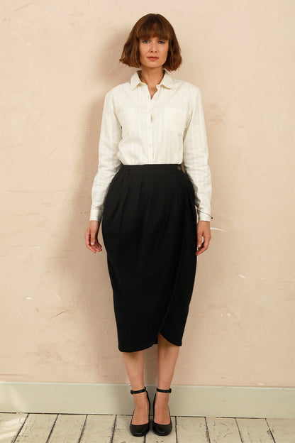 Full-length front view of model wearing the black handwoven Venus Skirt styled with a white collared shirt