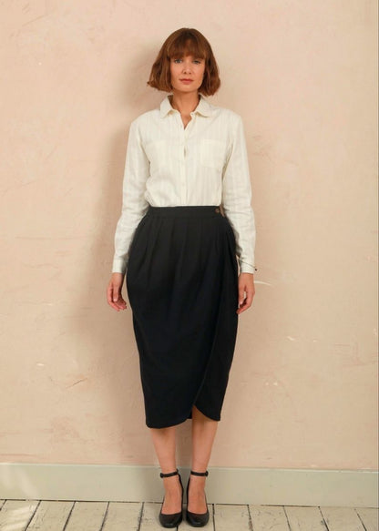 Full-length front view of model wearing the black handwoven Venus Skirt styled with a white collared shirt