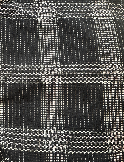 A close-up of a woven fabric with a black base and white plaid pattern.